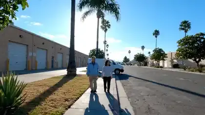 A quiet low-rise light-industrial street in southern California with palms moving in the breeze